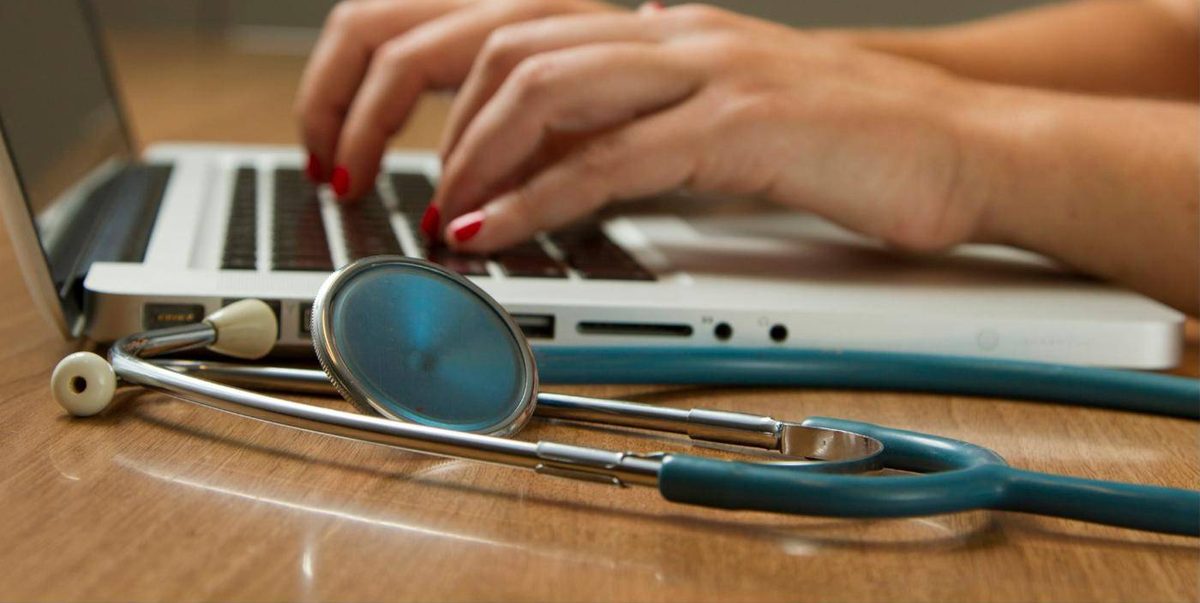 Consulta médica online desde un portátil con estetoscopio sobre la mesa